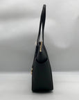 Black handbag with a gold clasp on a light gray background