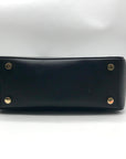 Black handbag with gold studs on a white background