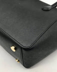 Black handbag with gold accents on a light gray background