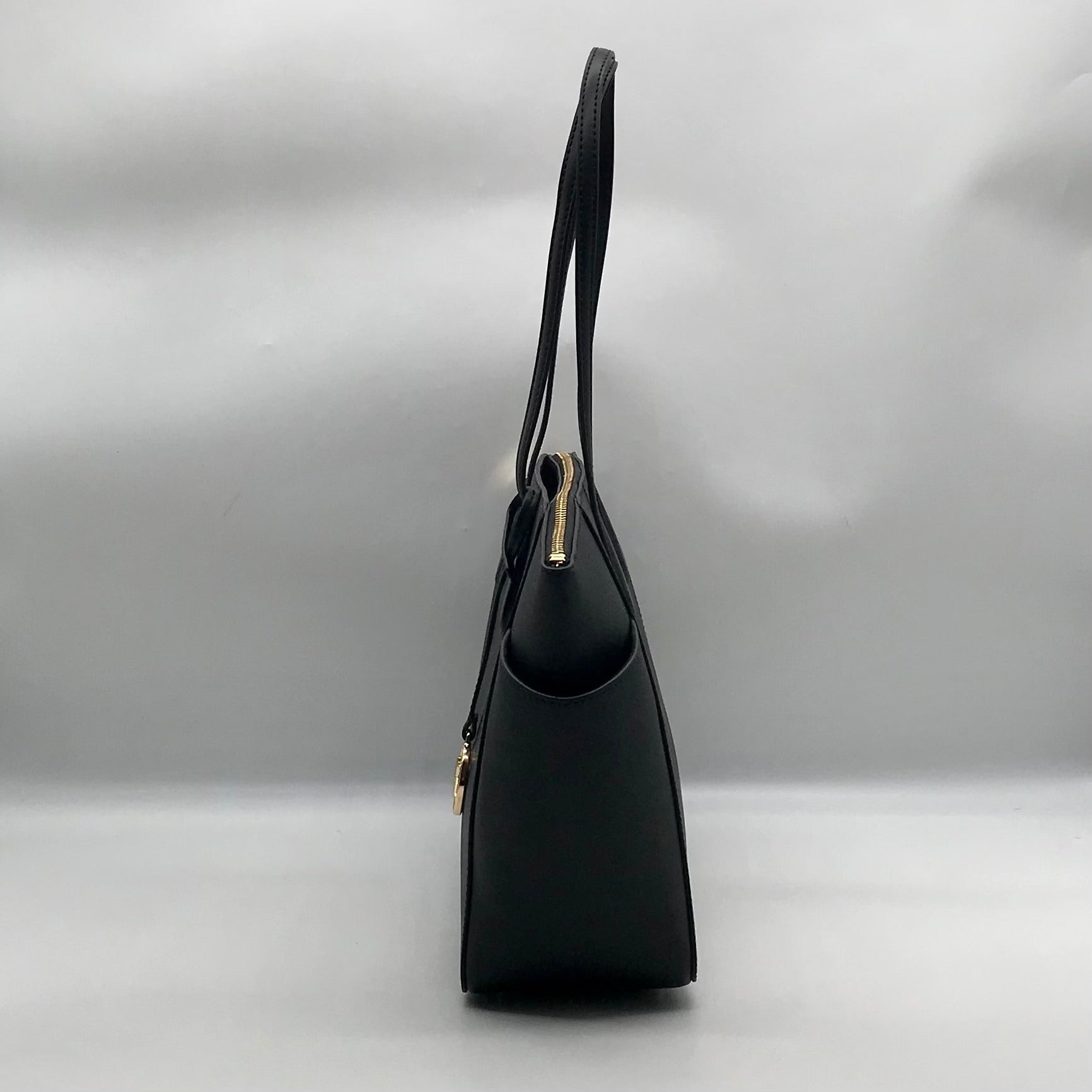 Black handbag with a gold clasp on a light gray background