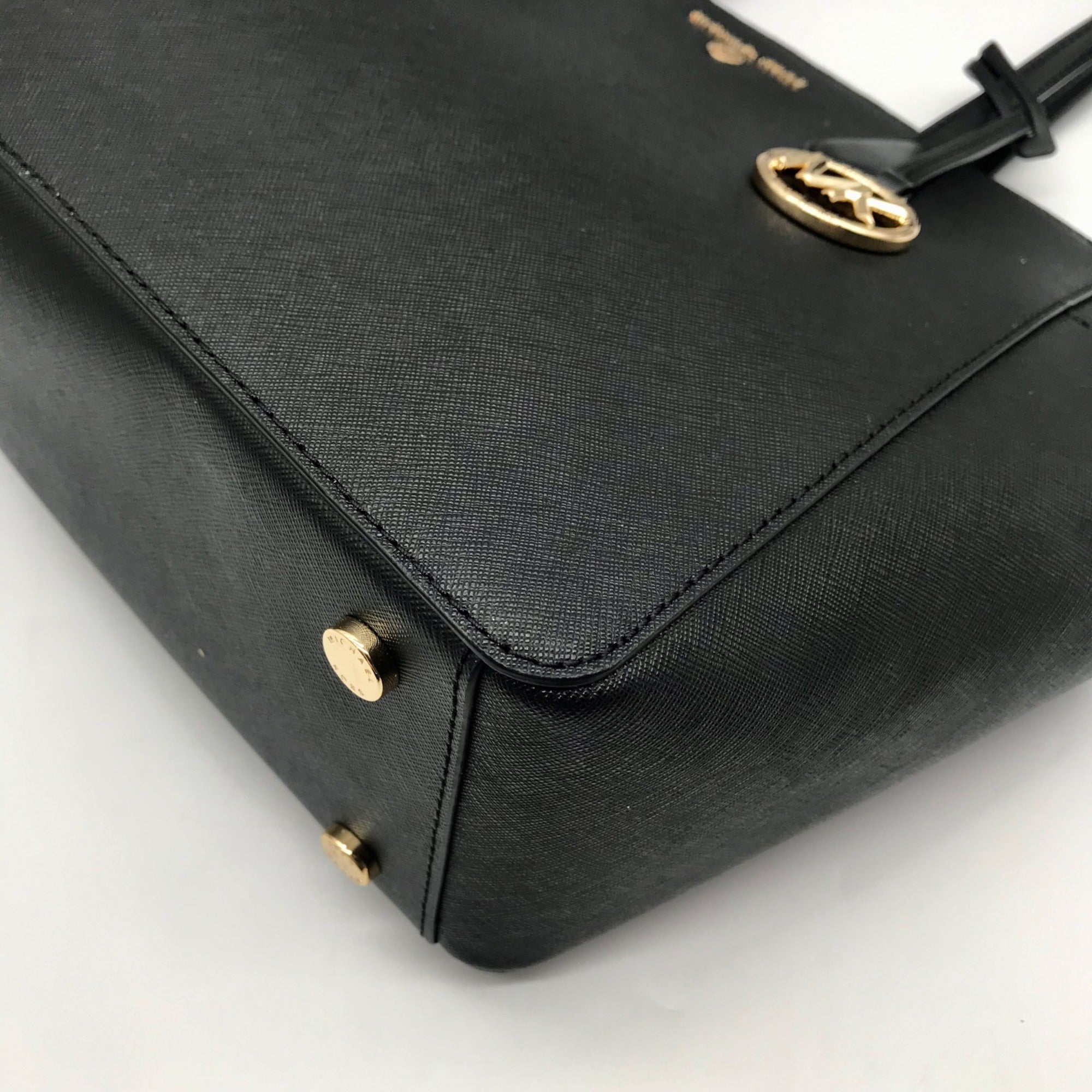 Black handbag with gold accents on a light gray background