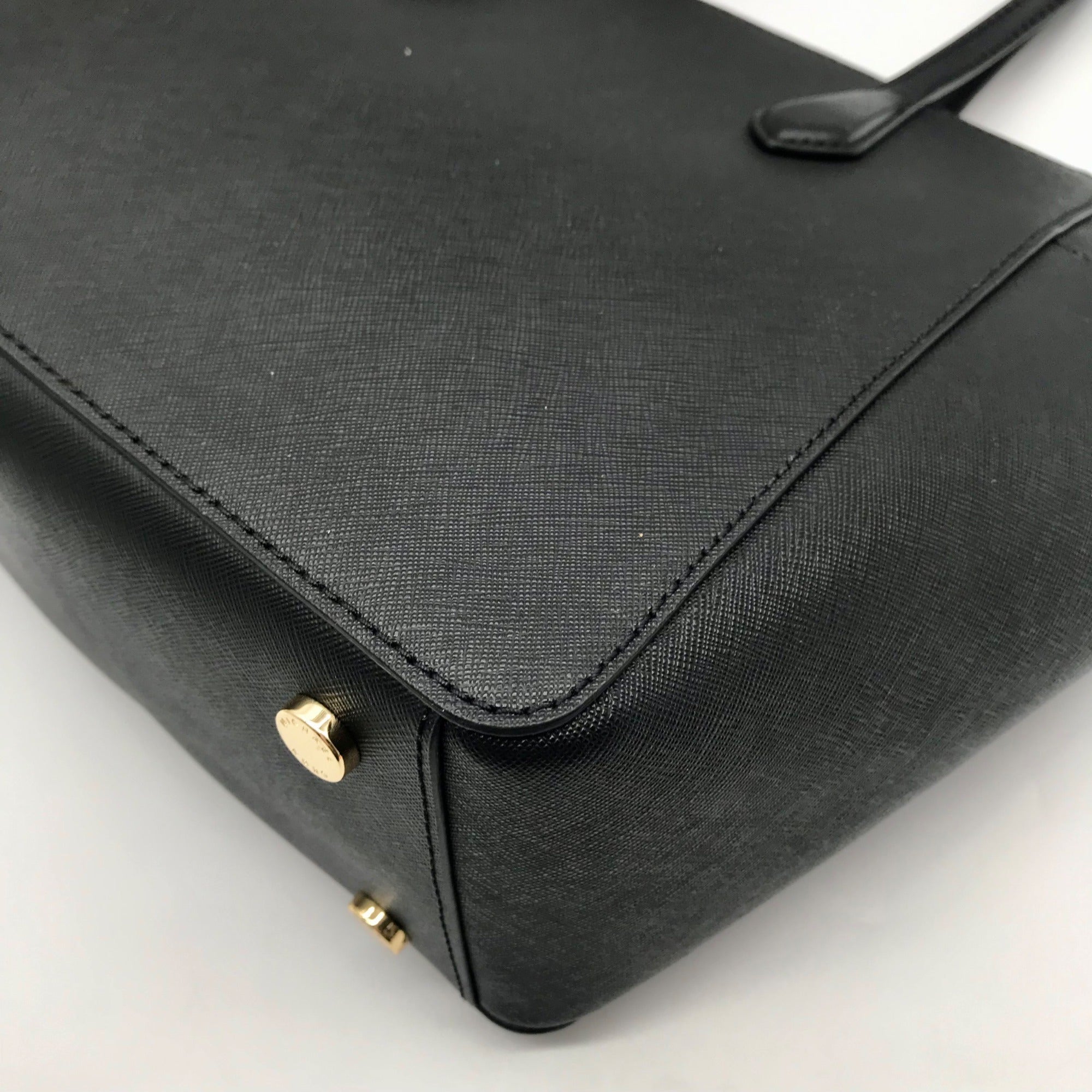 Black handbag with gold accents on a light gray background