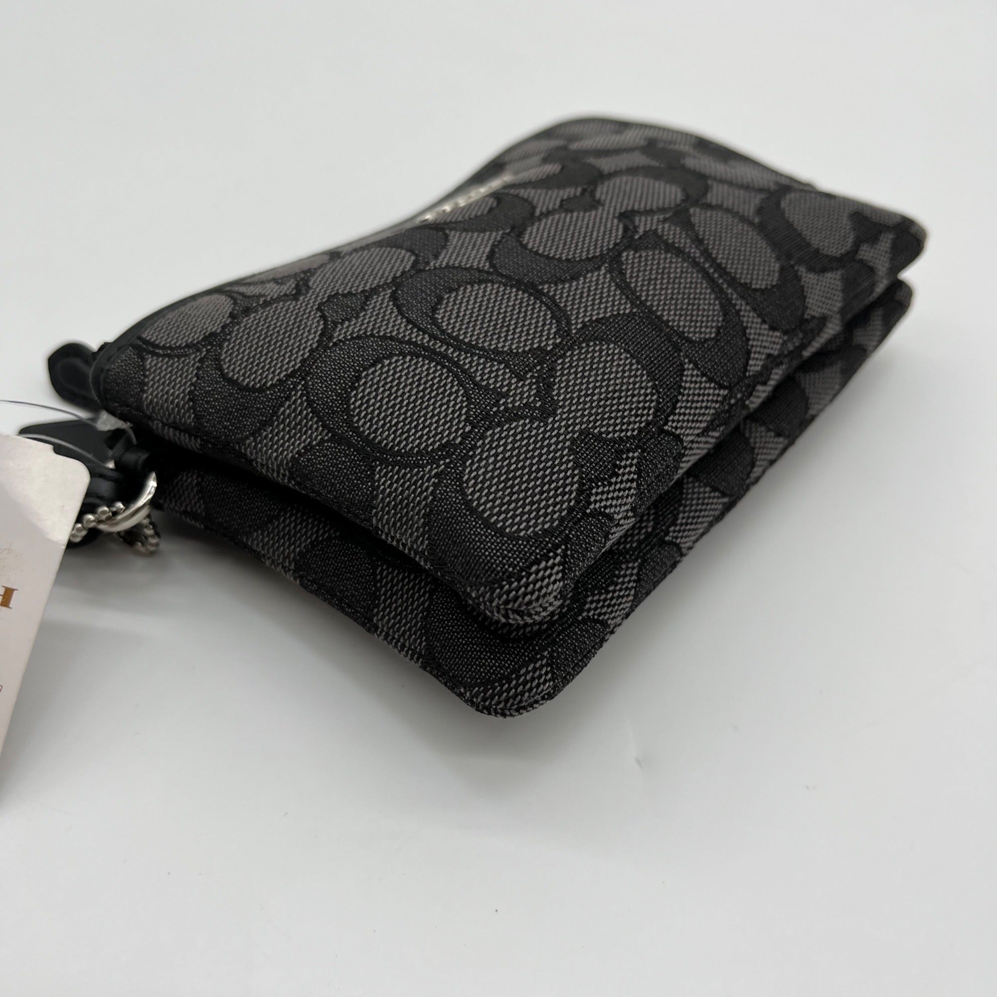 Black patterned wallet with a tag on a light gray background